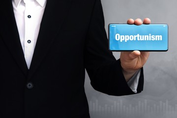 Opportunism. Businessman holding a phone in his hand. Man present screen with word. Blue Background. Business, Finance, Statistics, Analysis, Economy