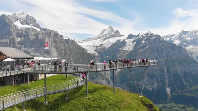 Tourists take pictures at the top of the first summit, in the background the Alps covered with snow, Switzerland, summer