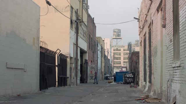 Man throws away trash in LA alleyway