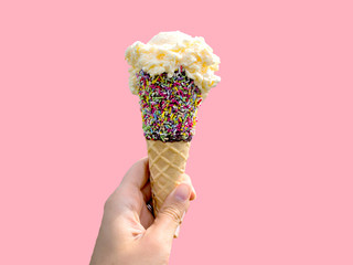 female holding ice cream with chocolate and sprinkles cone on pink background