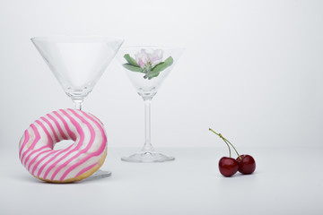  A flower in a glass close-up for a screensaver. In the background is a donut glass. And next to it is sweet cherry.