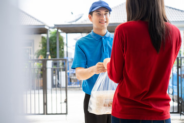 Food Delivery man wearing mask handing plastic bags shopping online from supermarket to female client service customer front house, express grocery when coronavirus covid19 new normal lifestyle.