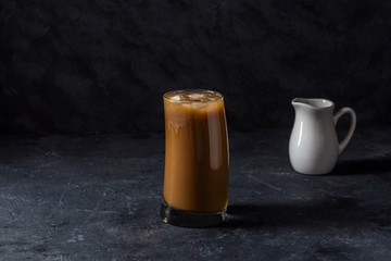 Ice coffee frappe in tall glass. Cool summer drink on a dark background in low key. Close up, copy space for text