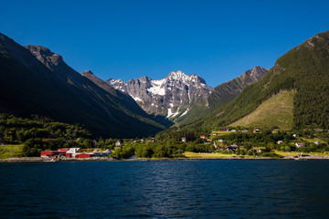Picturesque scene of Urke village and Hjorundfjorden fjord, Norway. Drammatic sky and gloomy mountains. Landscape.