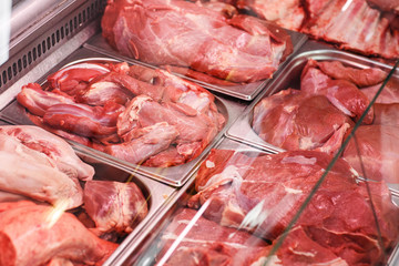 Heap of fresh meat food meat food background in supermarket store. Different types of raw meat in plastic boxes, leg of lamb on the bone, beef tail, beef neck, beef blade. Concept of farm and raw