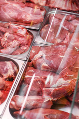 Heap of fresh meat food meat food background in supermarket store. Different types of raw meat in plastic boxes, leg of lamb on the bone, beef tail, beef neck, beef blade. Concept of farm and raw