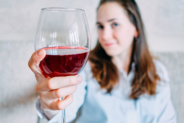 Girl holds a glass and smiles on the sofa