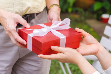 People giving red present box on holiday occasion. 