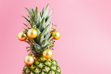  golden christmas balls on pineapple, pink background. pineapple like a christmas tree. Christmas...
