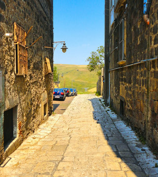  narrow street between old buildnigs and beautiful view on green hills around small town Venosa in Basilicata, South Italy         