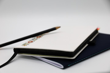 Two notebooks and a pencil with a white background