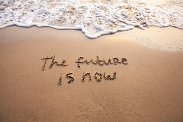 Fototapeta na wymiar the future is now, innovative technology concept text written on sand