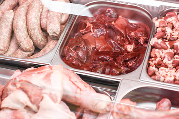 Heap of fresh meat food meat food background in supermarket store. Different types of raw meat in plastic boxes, leg of lamb on the bone, beef tail, beef neck, beef blade. Concept of farm and raw