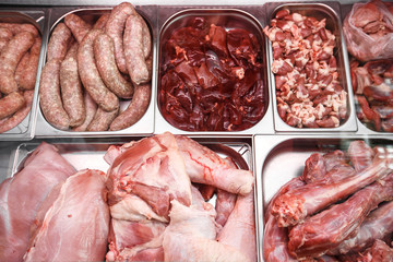 Heap of fresh meat food meat food background in supermarket store. Different types of raw meat in plastic boxes, leg of lamb on the bone, beef tail, beef neck, beef blade. Concept of farm and raw