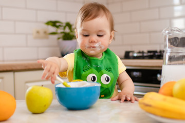 Happy child girl in the kitchen eats a delicious cottage cheese and porridge.