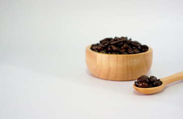 Fototapeta na wymiar Roasted coffee beans in a wooden cup and spoon on a translucent background