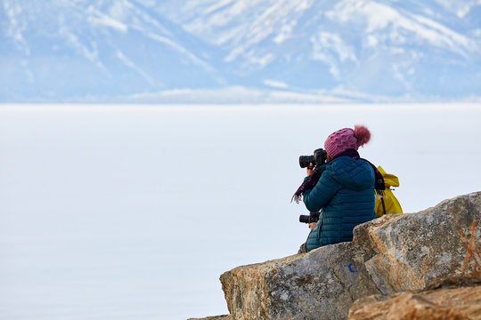 Photographers sit on a rock against the backdrop of mountains