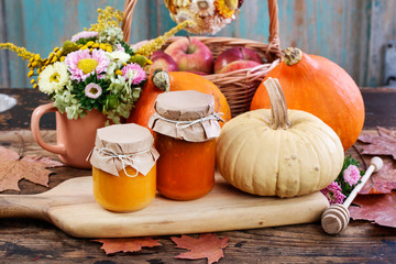 Glass jars with pumpkin jam and honey. Fresh vegetables on the table.