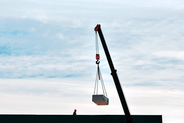 Crane lifts materials for construction and decoration of building on the roof. Crane with raised...