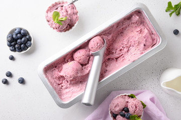 Blueberry homemade ice cream in metallic tub on white background. View from above. Clean eating....