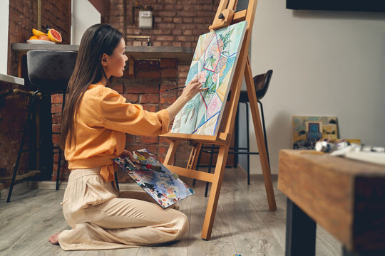 Talented female artist painting picture at home