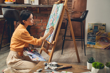 Charming young lady painting picture at home - Powered by Adobe