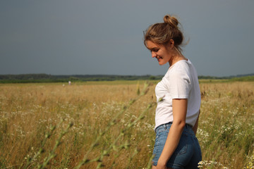 Naklejka na ściany i meble portrait of a blond charming beautiful woman in white t-shirt and jeans shorts in the wheat field .
