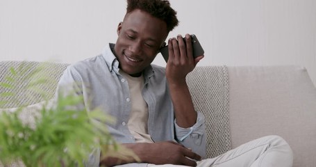 Black guy listening voice message on cellphone, sitting at home