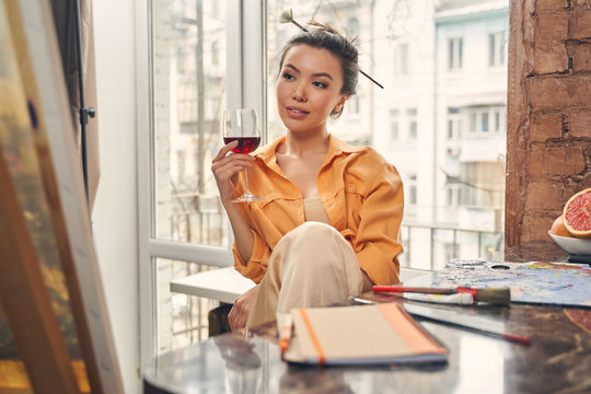 Attractive young woman drinking wine at home