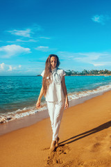 young female rescuer with stethoscope on the neck on the beach coast in sunny day is walking  near...