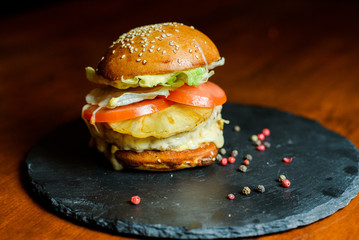 hamburger with chicken, pineapple and vegetables on a plate