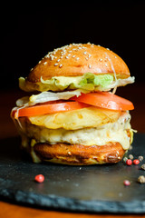 hamburger with chicken, pineapple and vegetables on a plate