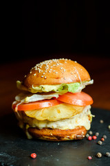 hamburger with chicken, pineapple and vegetables on a plate