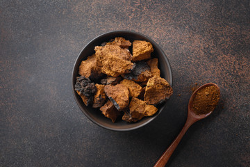 Chaga birch Mushrooms in bowl on black table. Trendy healthy superfood for infusion, tea or coffee....
