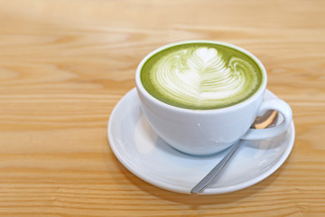 Matcha Japanese Green tea with cream milk form art on wood table.
