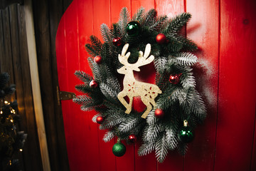 Christmas wreath with decor and festive deer on red door