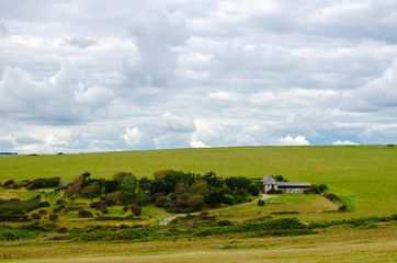 English landscape. Hill covered with green grass and cloudy sky. 