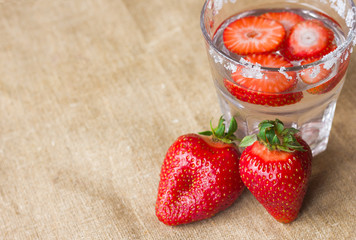  A refreshing drink of strawberries in a glass and berries on a background of canvas made from...