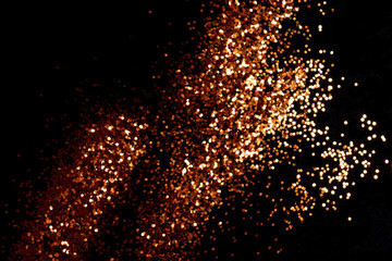 Fototapeta na wymiar Glowing golden glitter scattered on a black background. Holidays creative composition.