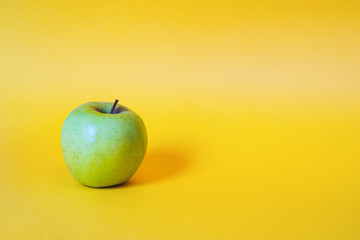 Single apple on yellow background