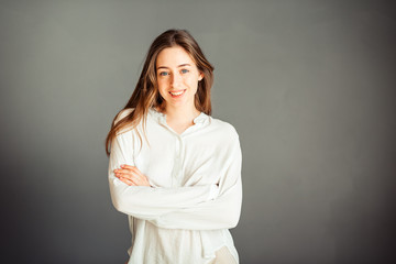 Young girl in a white shirt, hands up, on a gray background. Honest and emotional on the banner, billboard, billboard. No retouch. Without make-up.