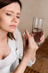 selective focus of pregnant woman holding vitamins pill and glass of water