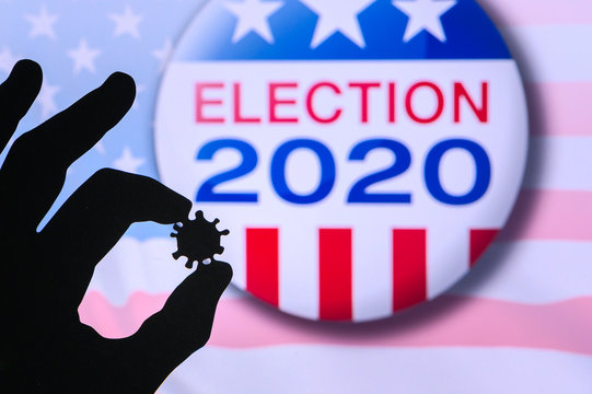 Hand silhouette hold covid 19 virus. Logo of USA presidental Election 2020 in background. US presidential elections are threatened by coronavirus and may be postponed