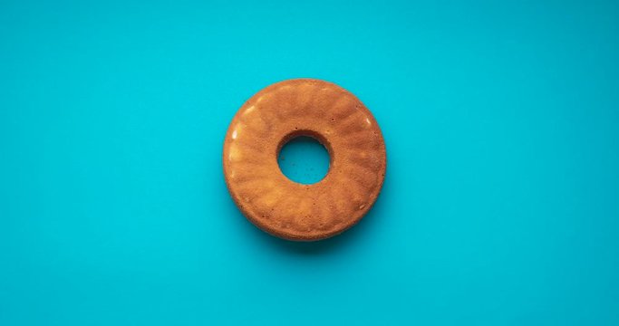 Cornmeal bundt cake stop motion, isolated on blue background. Flat lay animation of Festa Junina food. Brazilian cornmeal dessert. Bolo de fuba. 
