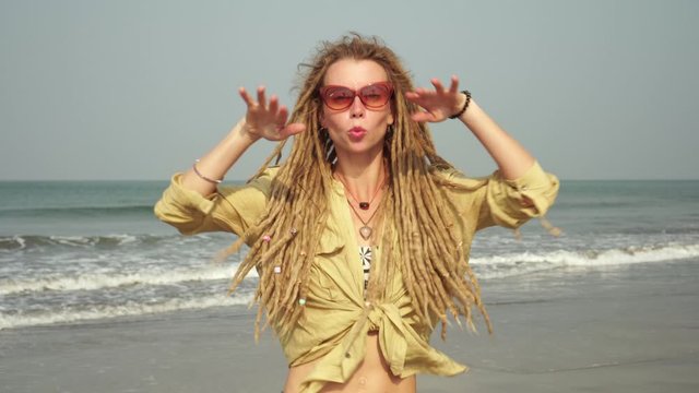 A young hippie woman is dancing on the beach. Hipster girl with dreadlocks