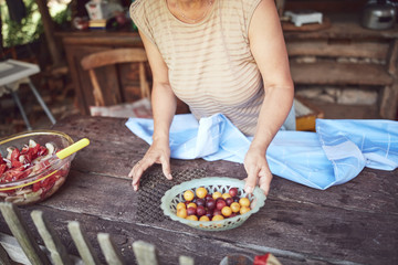 Woman preparing food and feast for summertime lunch at countryside rustic cottage outdoor kitchen.