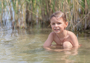 Happy little boy is swimming in the lake