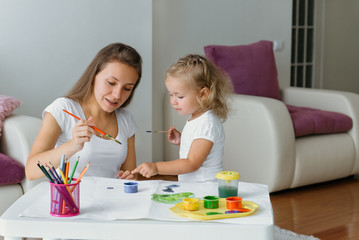 Obraz na płótnie Canvas Mother and toddler child painting at home, creative family
