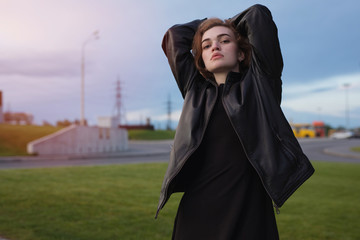 Portrait of woman in leather jacket at the evening sky
