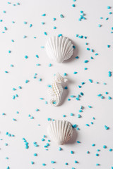 sea shell and seahorse in white color surrounded by small turquoise blue stones on bright background, Summer concept.